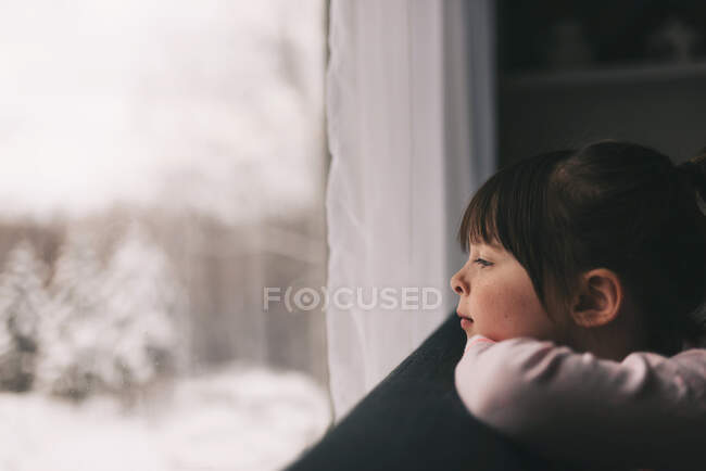 Fille regardant par une fenêtre en hiver — Photo de stock