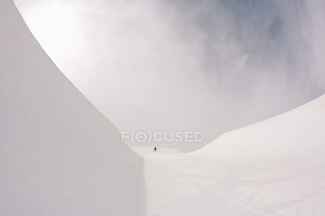 Nuvens brancas no céu sobre montanhas nevadas com pessoa caminhando distante — Fotografia de Stock