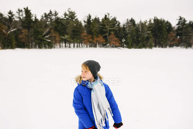 Retrato de un niño parado en un lago congelado - foto de stock