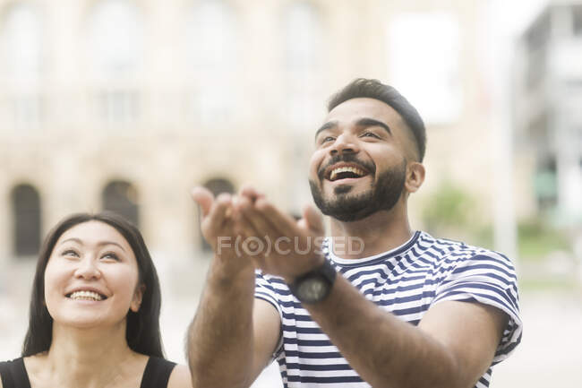 Smiling couple standing in city square throwing rice in the air — Stock Photo