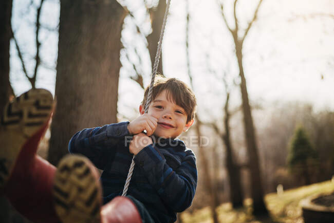 Крупным планом портрет улыбающегося мальчика на качелях — стоковое фото