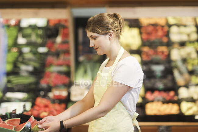 Asistente de ventas en la sección de frutas y hortalizas - foto de stock