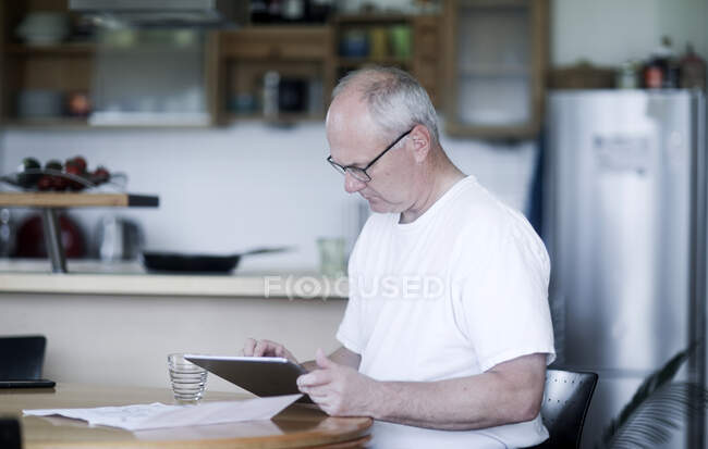 Homem sentado em uma mesa usando um tablet digital — Fotografia de Stock