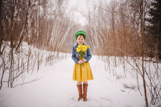 Smiling Girl standing in the snow holding a bunch of flowers — Stock Photo
