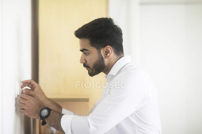 Man adjusting a control button on a wall — Stock Photo