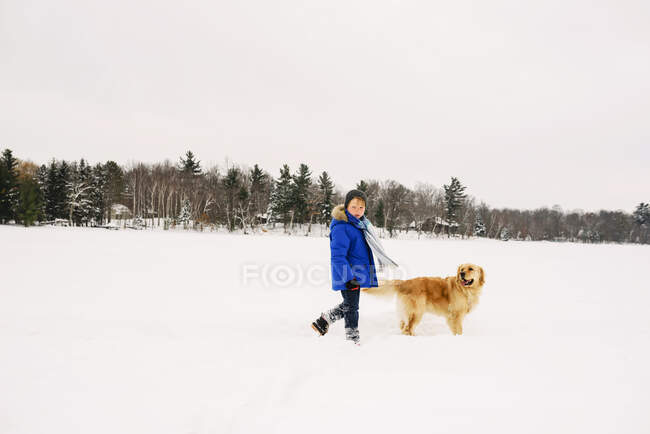Junge geht mit Hund im Schnee spazieren — Stockfoto