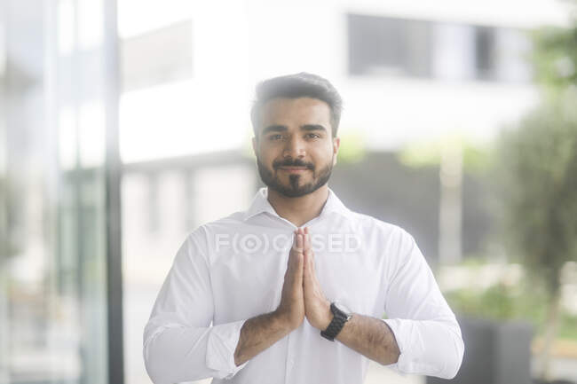 Smiling Businessman standing outdoors doing yoga — Stock Photo