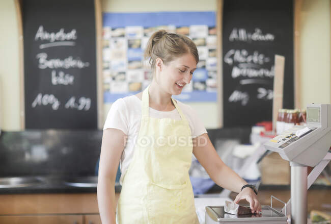 Sales assistant weighing a piece of cheese — Stock Photo