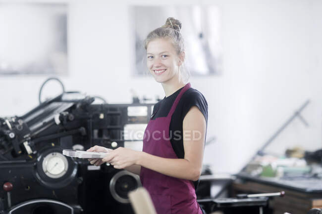 Smiling Woman operating a printing press in a factory — Stock Photo