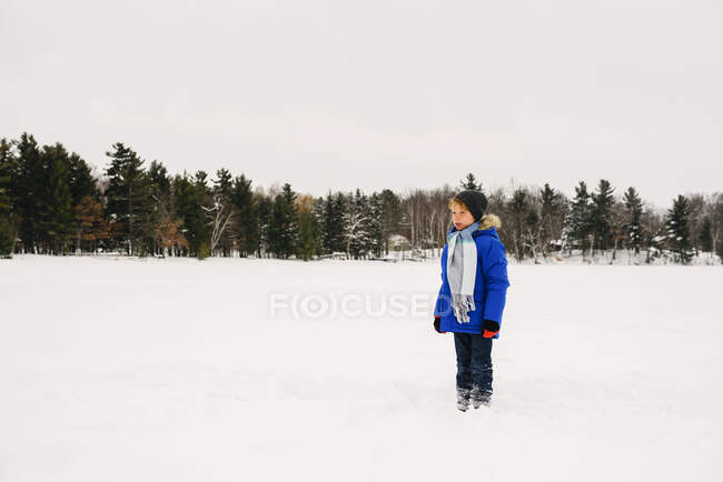 Мальчик, стоящий на замерзшем озере — стоковое фото