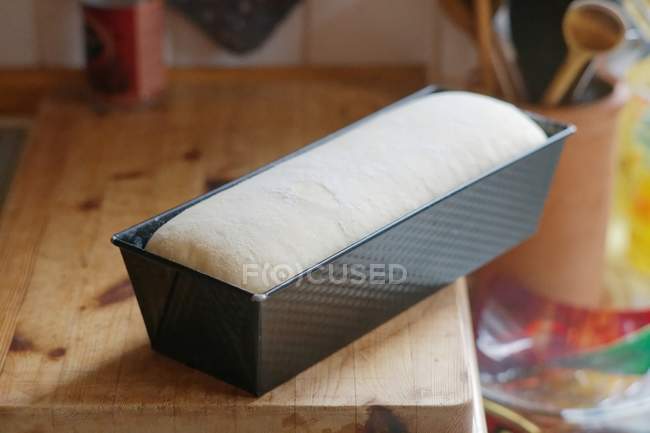 Loaf of raw bread dough in a baking tin — Stock Photo