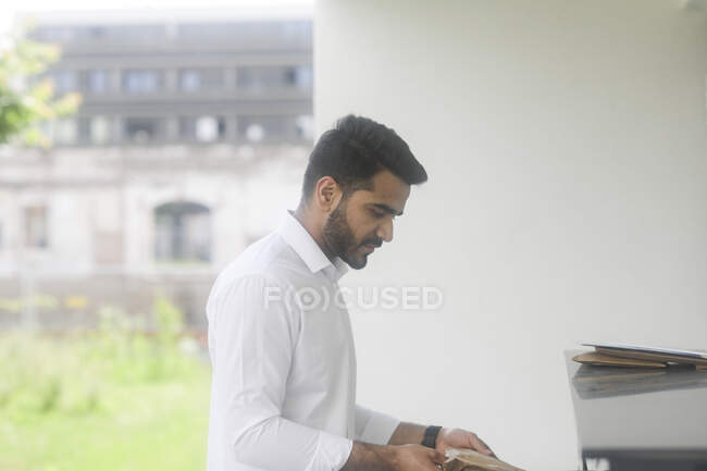 Man standing outdoors opening a mail box — Stock Photo