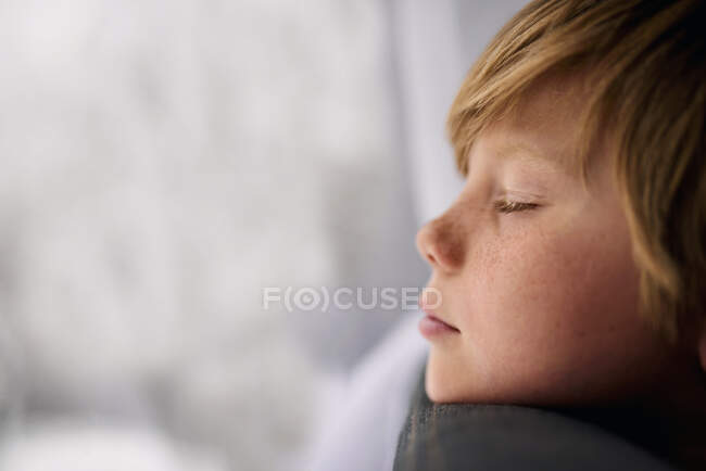 Хлопчик стоїть біля вікна з закритими очима — стокове фото
