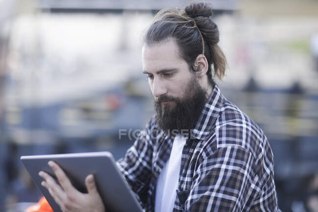 Homem sentado ao ar livre usando um tablet digital — Fotografia de Stock