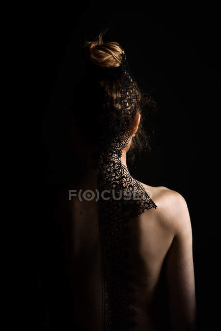 Rear view of a naked woman wearing a lace ribbon in her hair — Stock Photo