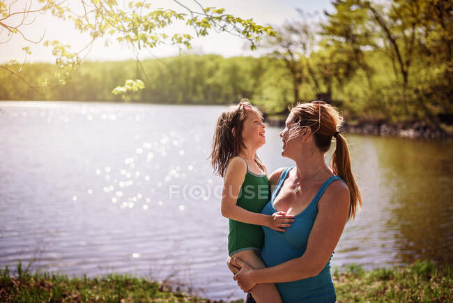 Мать стояла у озера, неся дочь. — стоковое фото