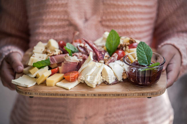 Girl holding a cheese and cured meat antipasto board — Stock Photo