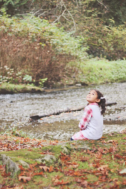 Ragazza seduta vicino a un torrente in autunno, Pacifico nordoccidentale, Stati Uniti — Foto stock