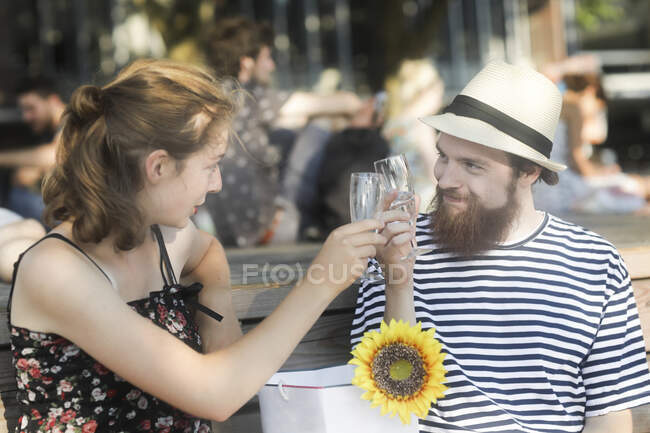 Portrait of a smiling couple sitting on a bench making a celebratory toast — Stock Photo