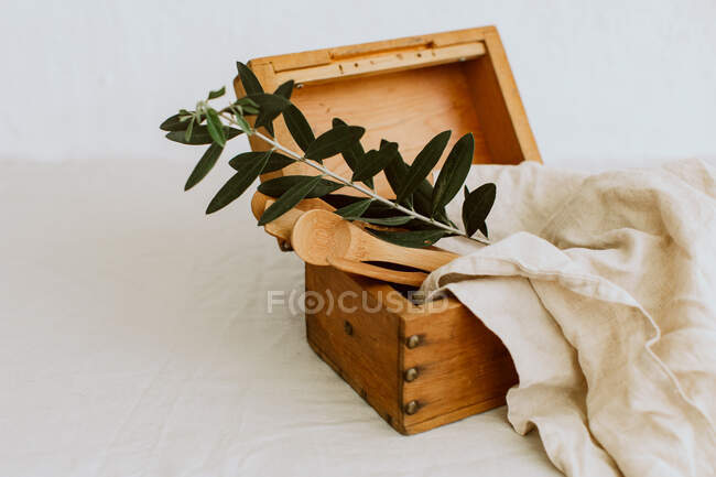 Alte rustikale Schachtel auf Leinentischdecke mit hölzernen Küchenutensilien — Stockfoto