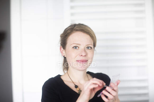Жінка стоїть у ванній, застосовуючи блиск для губ — стокове фото