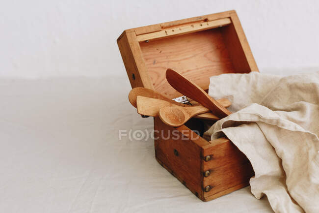 Wooden box with kitchen utensils and a linen napkin — Stock Photo