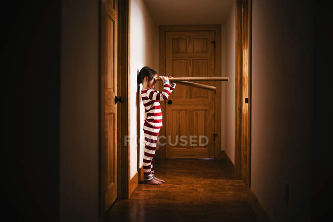 Mädchen steht im Hausflur und spielt mit Pappröhren — Stockfoto