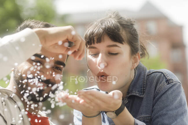 Smiling couple blowing a handful of confetti — Stock Photo