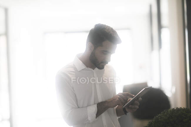 Чоловік стоїть в офісі з цифровою табличкою. — стокове фото