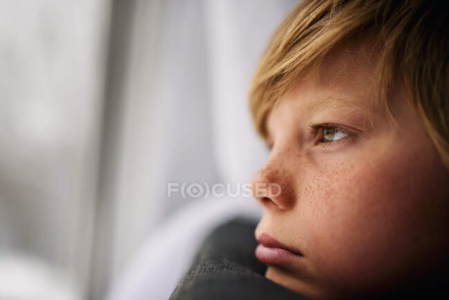 Хлопчик дивиться з вікна взимку — стокове фото