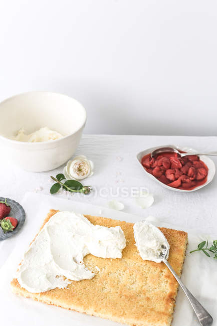 Sponge cake being covered with cream, closeup view — Stock Photo