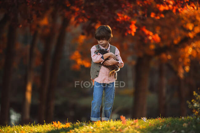 Boy standing outdoors cuddling a chicken, United States — Stock Photo