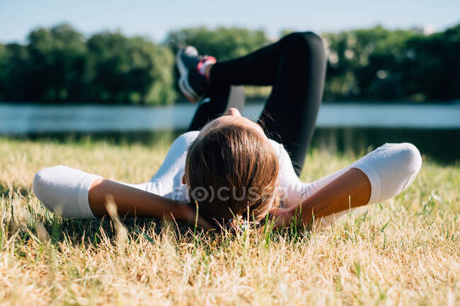 Donna sdraiata sull'erba in un parco rilassante — Foto stock