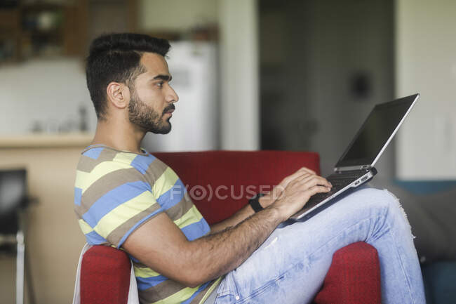 Чоловік сидить у кріслі, що працює на своєму ноутбуці — стокове фото