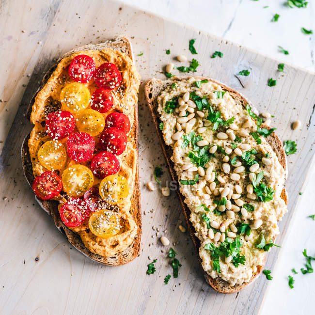 Hummus toasts with cherry tomatoes, pine nuts and parsley — Stock Photo