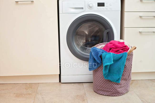 Cesta de lavandaria na frente de uma máquina de lavar roupa — Fotografia de Stock