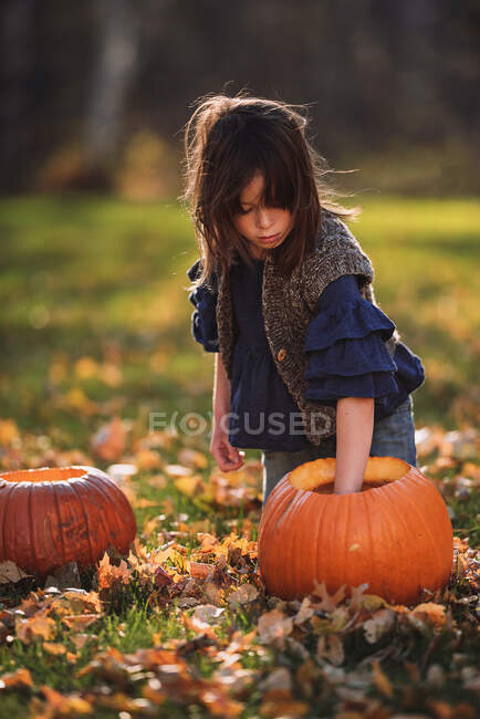 Дівчинка, що різьблює Хелловін гарбуза в саду (США). — стокове фото