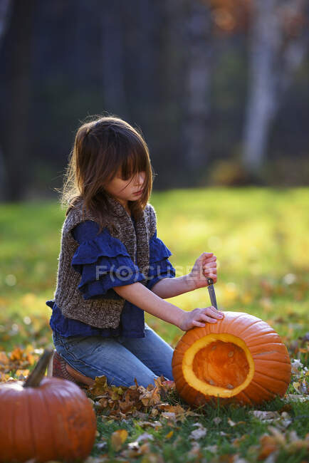 Girl carving a Halloween pumpkin in the garden, United States — Stock Photo