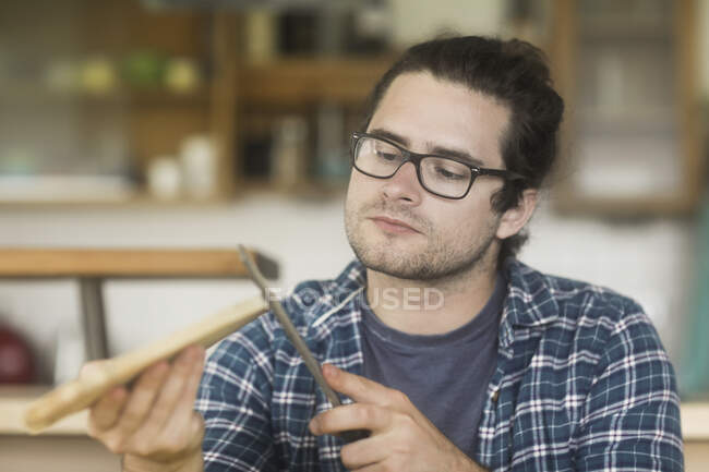Man sitting in living room making a wooden chopping board — Stock Photo