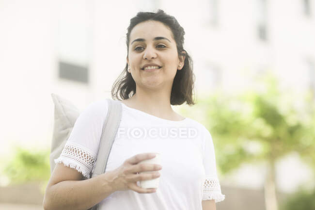 Портрет женщины, стоящей на улице с напитком — стоковое фото