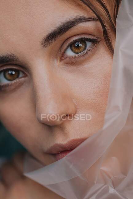 Retrato de una hermosa mujer detrás de plástico transparente - foto de stock