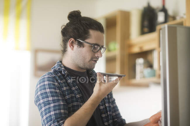 Portrait of a man holding carrots talking into a mobile phone — Stock Photo