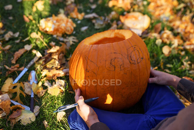 Garçon sculptant une citrouille d'Halloween dans le jardin, États-Unis — Photo de stock