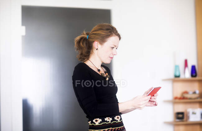 Woman standing in  bedroom using her mobile phone — Stock Photo