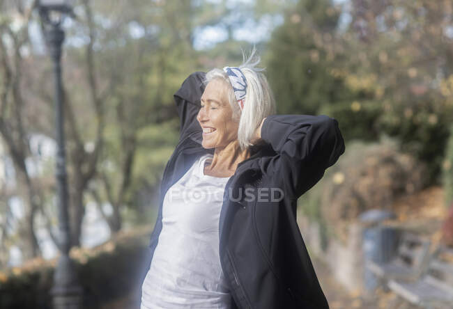 Woman standing in the park with her hands behind her head, Germany — Stock Photo