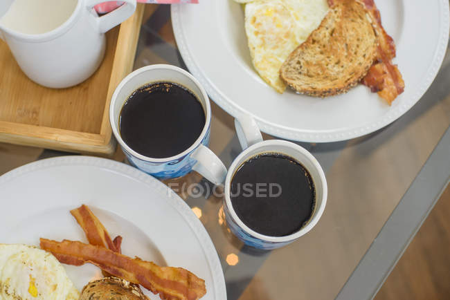 Huevo y tocino desayuno con café negro - foto de stock
