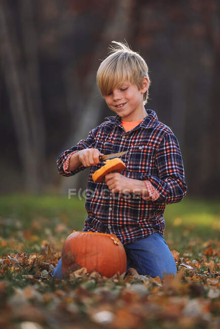 Усміхнений хлопчик вирізьблює на городі Хелловін (США). — стокове фото