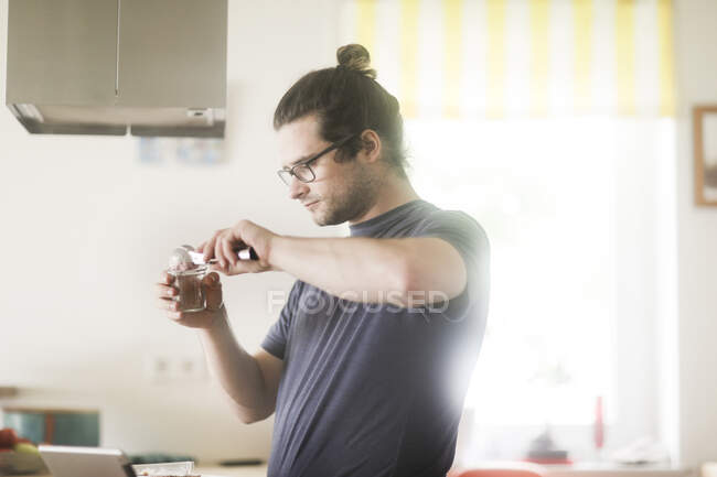Man standing in kitchen preparing ice-cream sundae dessert — Stock Photo
