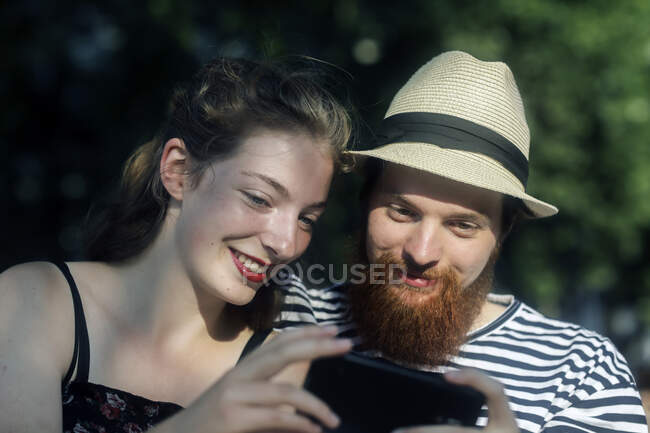 Lächelndes Paar schaut aufs Handy — Stockfoto