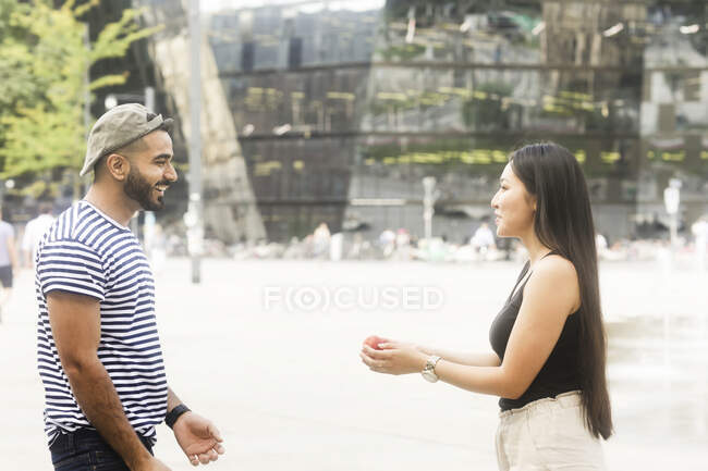 Couple standing in a city square playing with a ball — Stock Photo